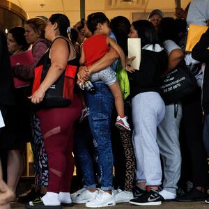 A group of migrants and members of the public wait in line outside an Illinois Department of Human Services office.