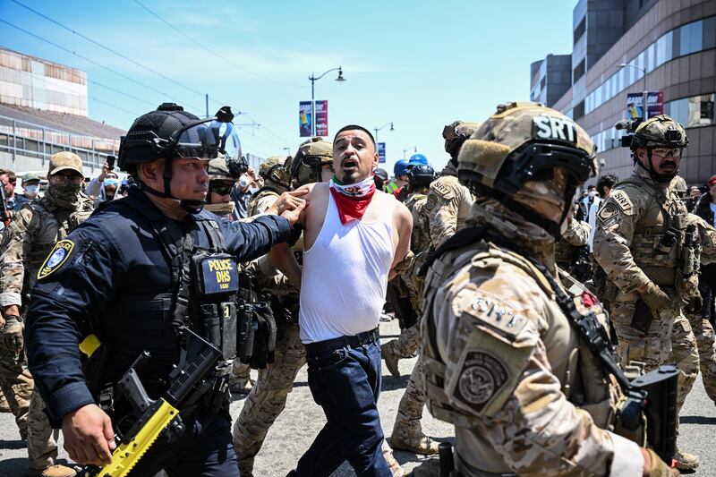Law enforcement officers, including members of the Immigration and Customs Enforcement (ICE) Special Response Team and Homeland Security agents, arrest a demonstrator outside the Federal Building in Los Angeles.