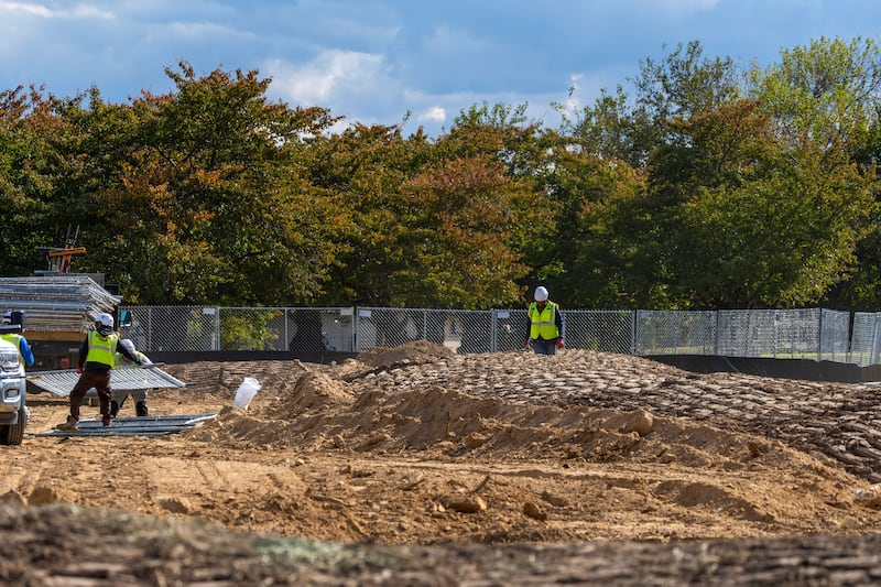WASHINGTON, DC - OCTOBER 24: Workers build a fence as trucks unload debris and soil from the demolition of the White House's East Wing at East Potomac Golf Course on October 24, 2025 in Washington, DC. The demolition is part of U.S. President Donald Trump's plan to build a multimillion-dollar ballroom on the eastern side of the White House. (Photo by Tasos Katopodis/Getty Images)