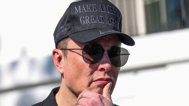 Tesla CEO Elon Musk looks on next to U.S. President Donald Trump talking to the media at the White House.
