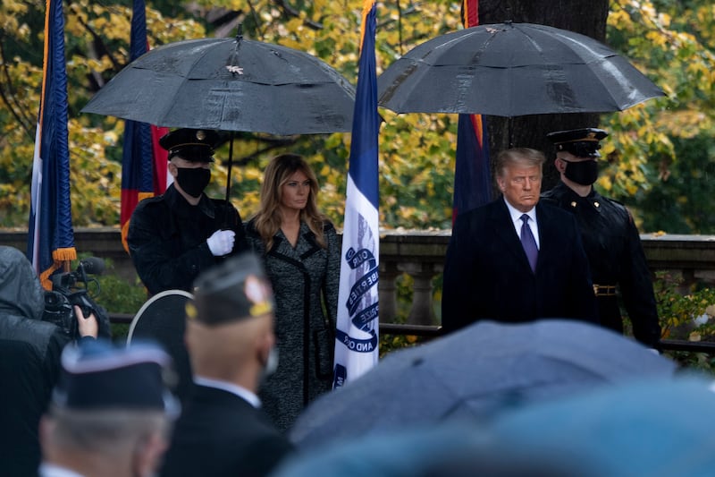 First Lady Melania Trump and President Donald Trump stand under umbrellas at the Tomb of the Unknown Soldier at Arlington National Cemetery.