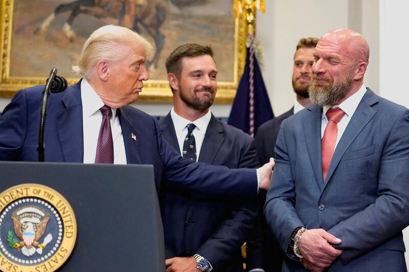 Donald Trump holds the arm of Paul Michael Levesque (Triple H), while delivering remarks at the White House.