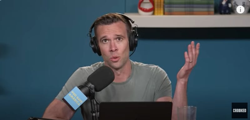 Jon Favreau, a former speechwriter for President Barack Obama, wearing headphones and talking into a mic during an episode of Pod Save America.