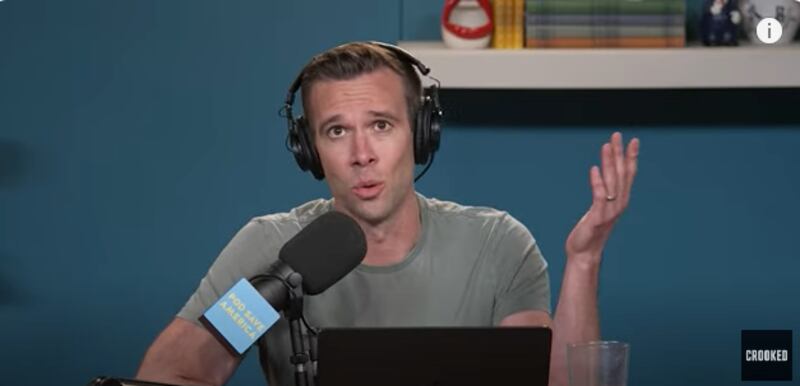Jon Favreau, a former speechwriter for President Barack Obama, wearing headphones and talking into a mic during an episode of Pod Save America.