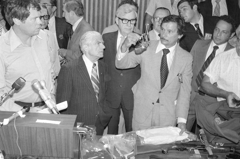 Arresting officer Det. Edward Zigo holds up .44-caliber revolver at a press conference after the arrest of David Berkowitz in the Son of Sam case.
