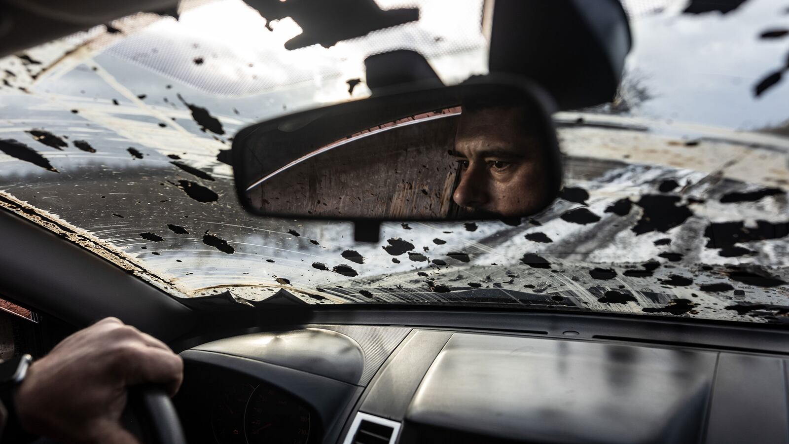 A Ukrainian soldier driving in Kupiansk can be seen in his rearview mirror