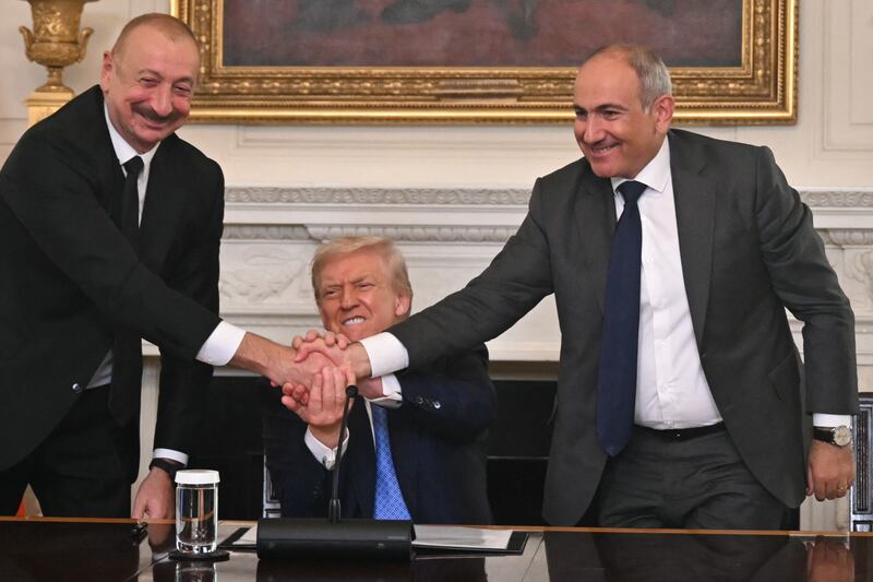 Donald Trump (C), Azerbaijani President Ilham Aliyev (L) and Armenian Prime Minister Nikol Pashinyan shake hands after signing an agreement in the State Dining Room of the White House in Washington, DC, on August 8, 2025.