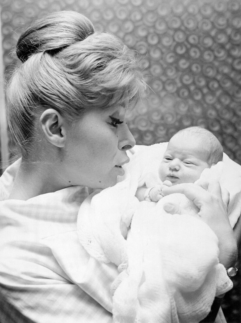 Shari Lewis, holds her petite redhead daughter Mallory, 4 days old, as they depart New York's Mt. Sinai Hospital for home