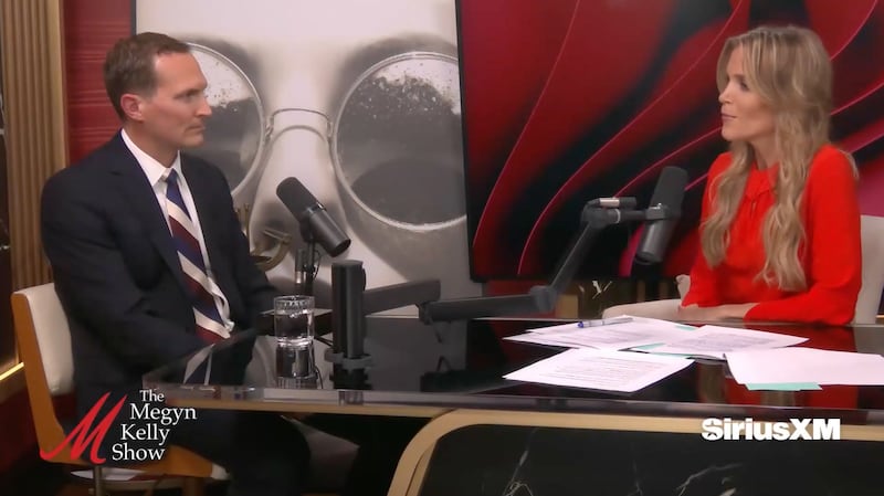 Colin Carroll and Megyn Kelly sit at a table facing each other while Kelly interviews Carroll.