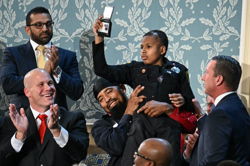 13-year-old cancer survivor Devarjaye "DJ" Daniel is lifted up by his father Theodis Daniel after given credentials from US Secret Service.