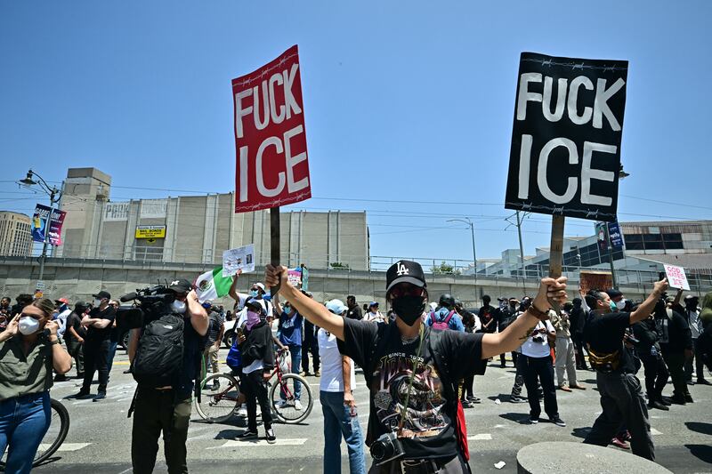 Protestors carring signs as they confront with National Guard soldiers and US Department of Homeland Security (DHS) Police officers, outside the Metropolitan Detention Center, MDC, in downtown Los Angeles, California on June 8, 2025.