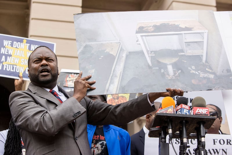 A picture shows attorney Michael Harper at a news conference where he's showing a picture of the poor conditions inside the Fulton County jail