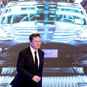 Elon Musk in front of a picture of a Tesla Model 3