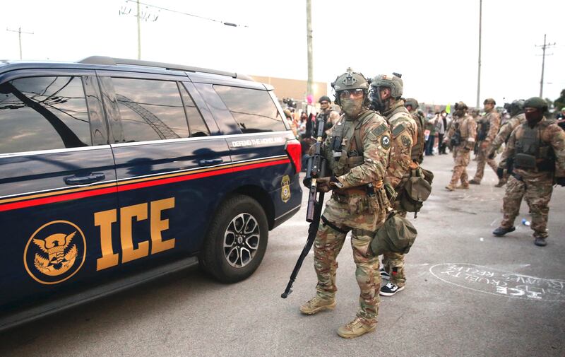Immigration and Customs Enforcement (ICE) agents armed with less-lethal weapons gather outside an ICE processing center during a protest in Broadview, Illinois