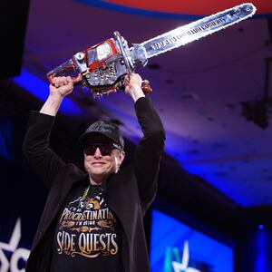 Elon Musk leaves the stage holding a chainsaw after speaking at the Conservative Political Action Conference (CPAC).