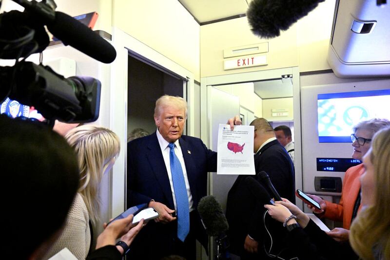 President Donald Trump speaks with journalists on board Air Force One.