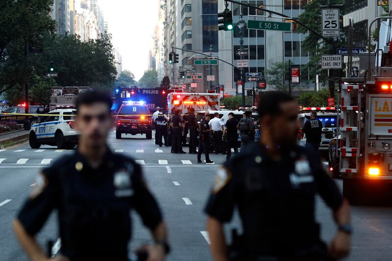 Police officers and emergency vehicles are seen in a street as police respond to a shooting incident in Midtown Manhattan on July 28, 2025.