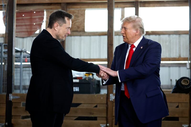 Elon Musk (L) shakes hands with President Donald Trump back stage during a campaign rally at the Butler Farm Show grounds on October 05, 2024 in Butler, Pennsylvania.