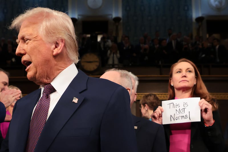 Rep. Melanie Stansbury (D-NM) holds a protest sign as Donald Trump arrives to address Congress.
