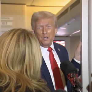 Trump addresses reporters aboard Air Force One.
