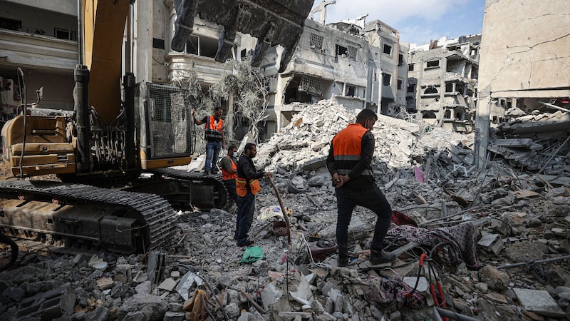 A photo including Palestinians searching for their belongings among the rubble in Gaza City