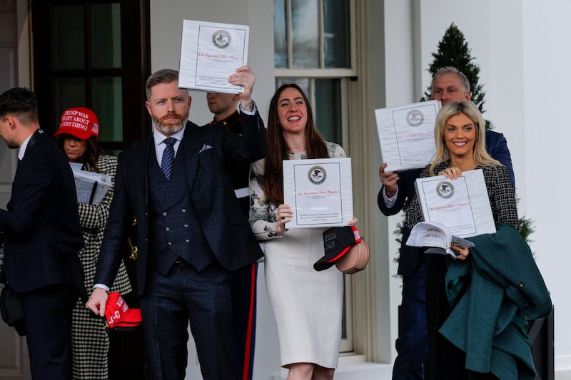 From left to right, Rogan “DC Draino” O‘Handley, Chaya Raichik, and Liz Wheeler show off a binder labeled as phase one of the “Epstein Files.” The binders did not contain new information, it was revealed after they met with President Donald Trump.