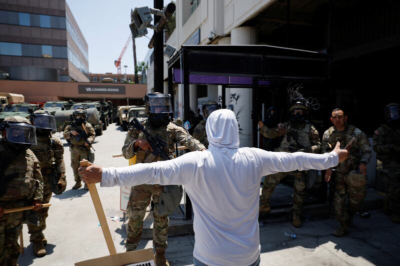 A demonstrator extends their arms during a protest against federal immigration sweeps, as members of the California National Guard stand outside the Edward R. Roybal federal building in Los Angeles.