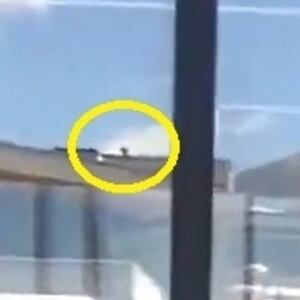 Still of video from scene of Charlie Kirk shooting, with person on roof circled in yellow.