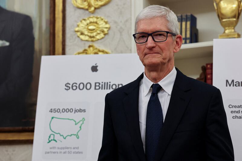 Apple CEO Tim Cook stands, as he along with U.S. President Donald Trump (not pictured) present Apple's announcement of a $100 billion investment in U.S. manufacturing, in the Oval Office at the White House in Washington, D.C., U.S., August 6, 2025.