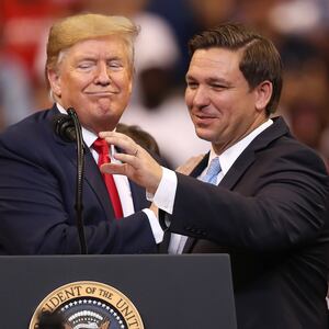 Donald Trump and Ron DeSantis stand in front of a podium.
