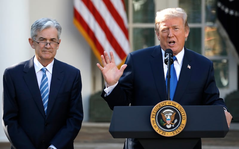 Donald Trump speaks at a podium next to Jerome Powell