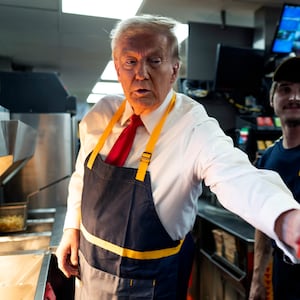 President Trump wearing a McDonald's apron hands fries to someone off camera.