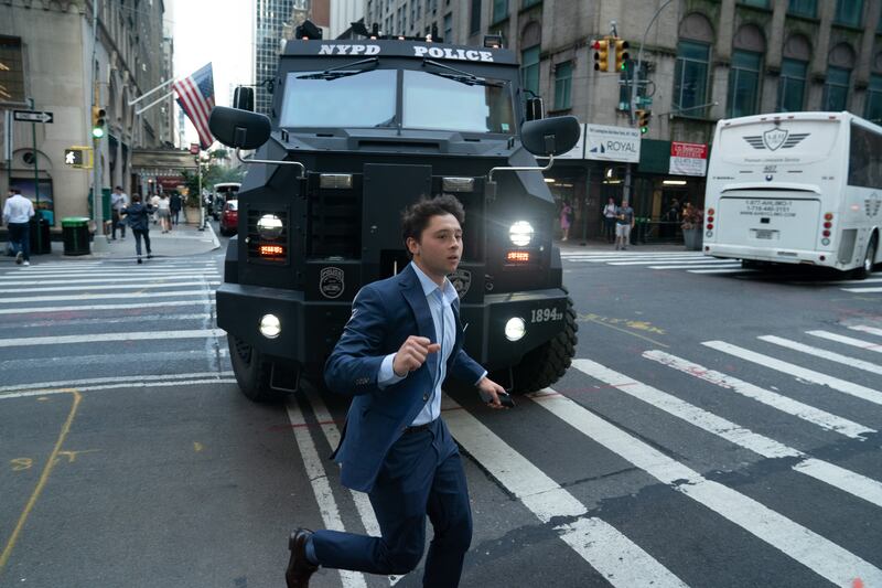 A fleeing office worker runs past a New York Police Department Bearcat as it arrives on the scene of an active shooter in Midtown Manhattan, Monday, June 28, 2025, in New York City.