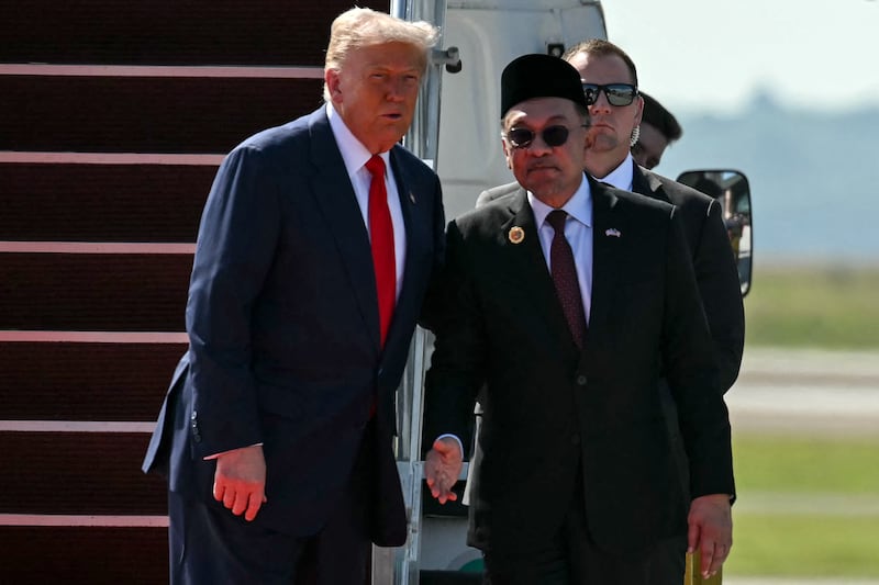 US President Donald Trump (L) speaks with Malaysia's Prime Minister Anwar Ibrahim (R) at the foot of the stairs of Air Force One upon arrival at Kuala Lumpur International Airport in Sepang on October 26, 2025. US President Donald Trump arrived in Malaysia on October 26 on the first leg of an Asian tour that will include high-stakes trade talks with Chinese counterpart Xi Jinping. (Photo by ANDREW CABALLERO-REYNOLDS / AFP) (Photo by ANDREW CABALLERO-REYNOLDS/AFP via Getty Images)