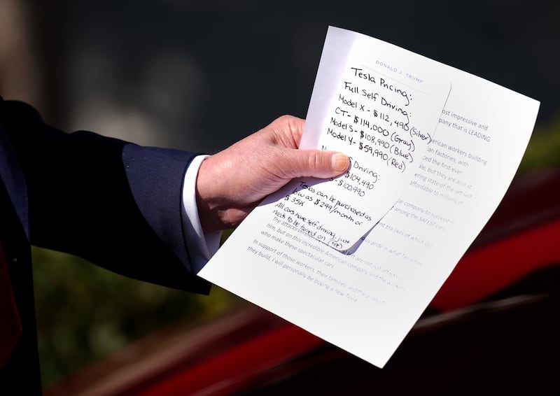 Donald Trump carried a note that included Tesla pricing during his White House stunt where he purchased a new car he says he will never drive.