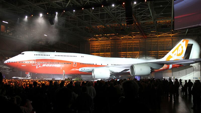 Boeing raises a curtain to unveil the 747-8 jumbo passenger jet to thousands of employees and guests at the company's Everett, Washington commercial airplane manufacturing facility, February 13, 2011. Boeing vice president and general manager of Boeing's Commercial Airplanes airplane program Pat Shanahan is pictured on the jumbo screen in the upper right as he officiated the ceremony. Boeing Co rolled out the new jumbo jet on Sunday, hoping to relive the glamor surrounding the birth of the 747 over 40 years ago and use it to boost slow sales. REUTERS/Anthony Bolante (UNITED STATES - Tags: TRANSPORT BUSINESS)
