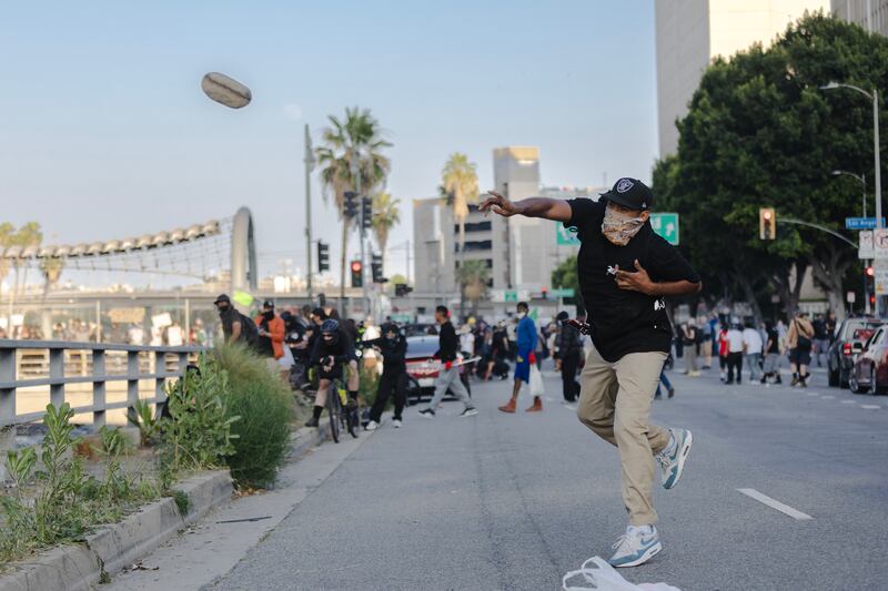 LOS ANGELES, CALIFORNIA - JUNE 8: A protester throws a rock at police who were staging on the 101 freeway during clashes on June 8, 2025 in Downtown Los Angeles, California. The clashes come after ICE raids swept throughout the city over the weekend. (Photo by Jim Vondruska/Getty Images)