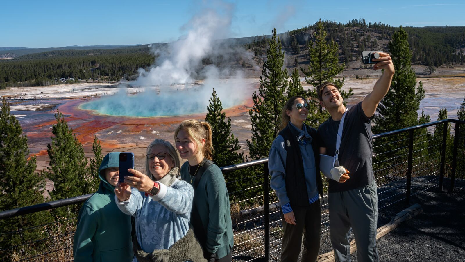 YELLOWSTONE NATIONAL PARK, WYOMING - OCTOBER 09: Tourists take a selfie with the Grand Prismatic Spring on October 9, 2024 in Yellowstone National Park, Wyoming. (Photo by Qian Weizhong/VCG via Getty Images)