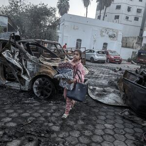 A girl tries to collect usable belongings amid wreckage of vehicles after Al-Ahli Baptist Hospital was hit in Gaza City, Gaza on Oct. 18, 2023.