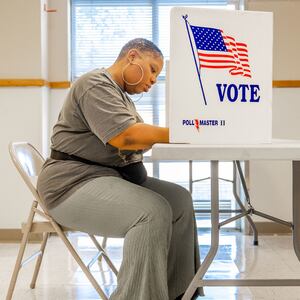 A woman seated at a polling station votes