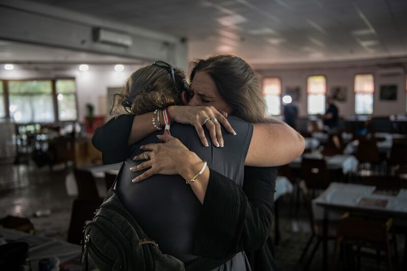 Two women embrace in a shelter.