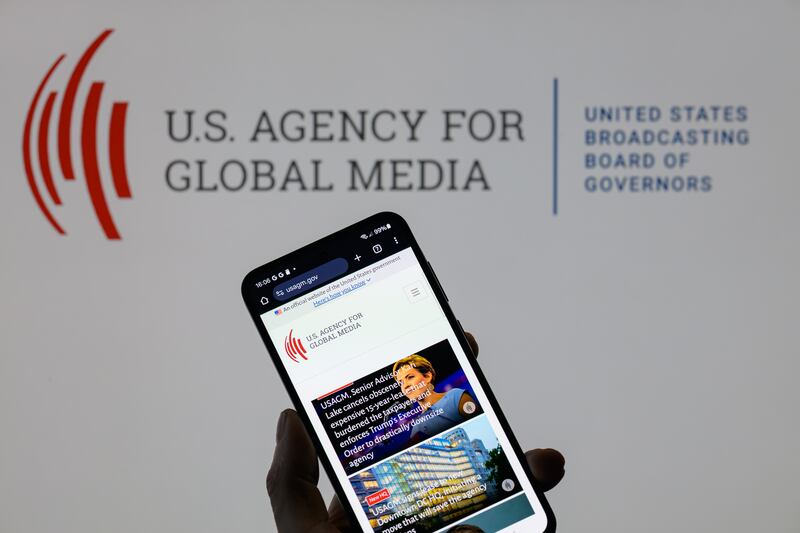 The US Agency for Global Media website displays on a mobile phone with US Agency For Global Media (USAGM) visible in the background, in this photo illustration in Brussels, Belgium, on March 16, 2025. (Photo by Jonathan Raa/NurPhoto via Getty Images)