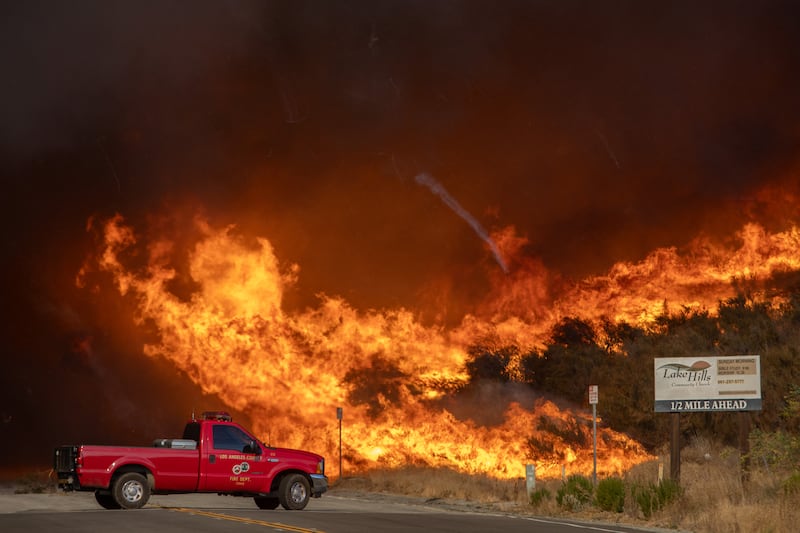 A firefighter truck backs up from flames of smoke.