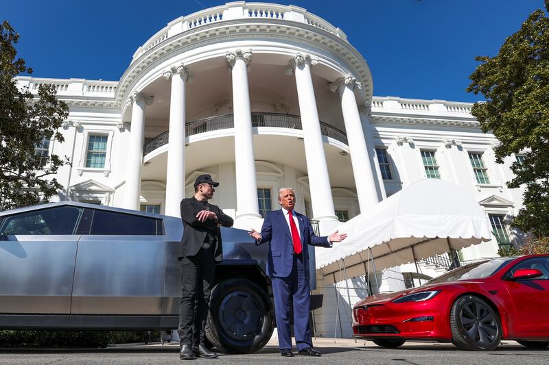 President Donald Trump talks to the media next to Tesla CEO Elon Musk, with Tesla cars in the background, at the White House in Washington, D.C. on March 11, 2025.