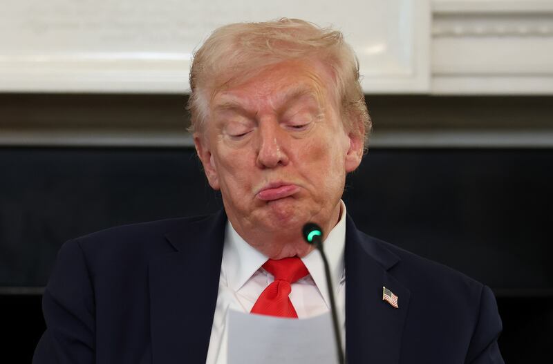 President Donald Trump reads a note during a roundtable discussion in the State Dining Room of the White House on October 08, 2025 in Washington, DC.