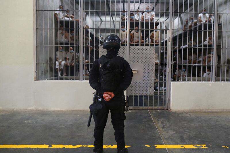 A policeman stands guard next to inmates inside a cell at the Terrorism Confinement Center (CECOT) prison, in Tecoluca, El Salvador April 4, 2025.