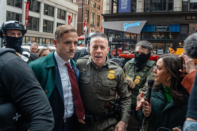 Border Patrol commander Gregory Bovino (C) pushes through a crowd of media and protesters as he enters the Dirksen Federal Building