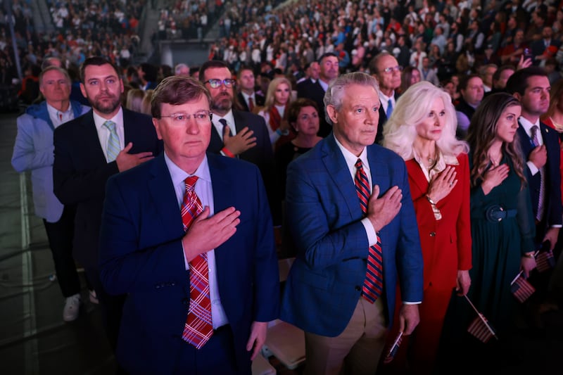 Governor of Mississippi, Tate Reeves, (L) stands with other attendees during the national anthem at a Turning Point USA event
