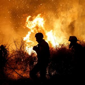 Firefighters work to put out a fire in an open field, following a mass-infiltration by Hamas gunmen from the Gaza Strip