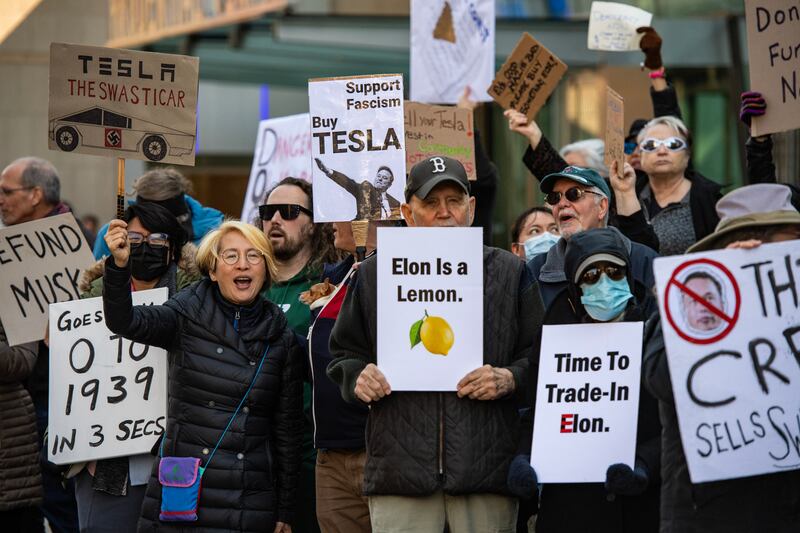 Protesters hold signs and sing chants during a protest against Elon Musk and his Tesla car company outside the Tesla dealership in Boston, Massachusetts on March 15, 2025.